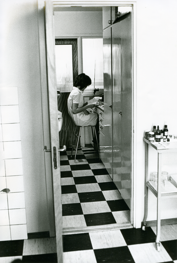 Arbetsplats för tandsköterskan mellan de båda tandläkarnas arbetsrum vid tandläkarmottagningen på Centralvägen 8. 
•Fotografiet ingår i bildserien ”Vardagsliv i Vallentuna kommun” av Rachael Gough-Azmier & Gunilla Blomé, Haga Studios HB.