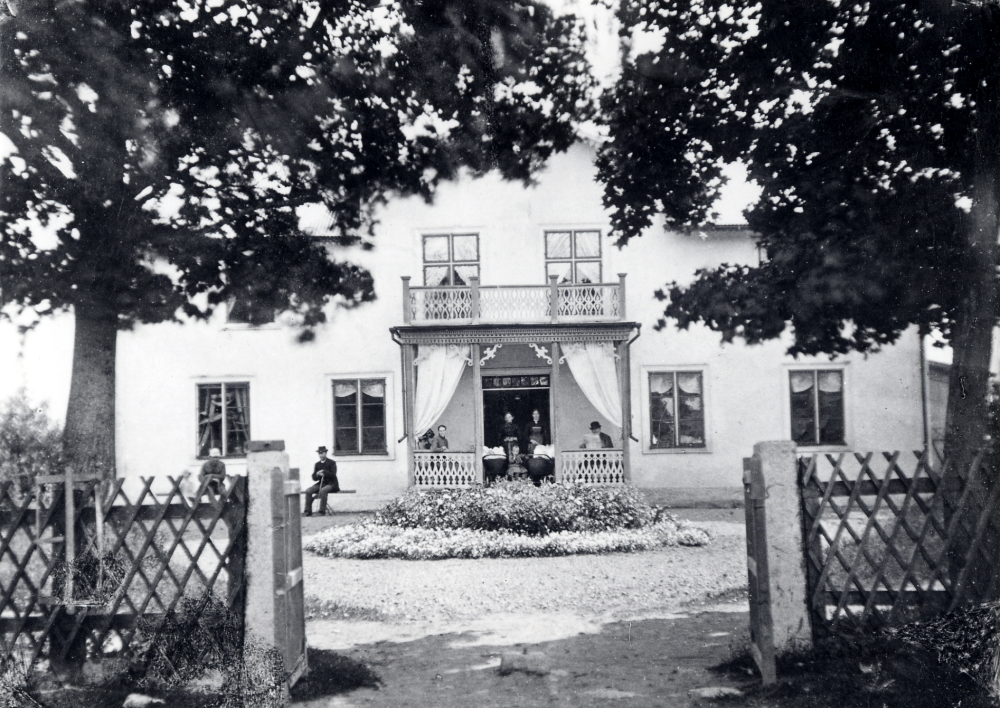 Stora Lundby gård i Markim. På bänken t h sitter Severin Åkerberg. På verandan sitter fr v Hilda Åkerberg, t h Severins hustru Selma Åkerberg, framför henne dottern Maria och Ellen i barnvagn. Robert Gustavsson längst t h Flera personer finns med på bilden, säkert om rätt person fått rätt namn