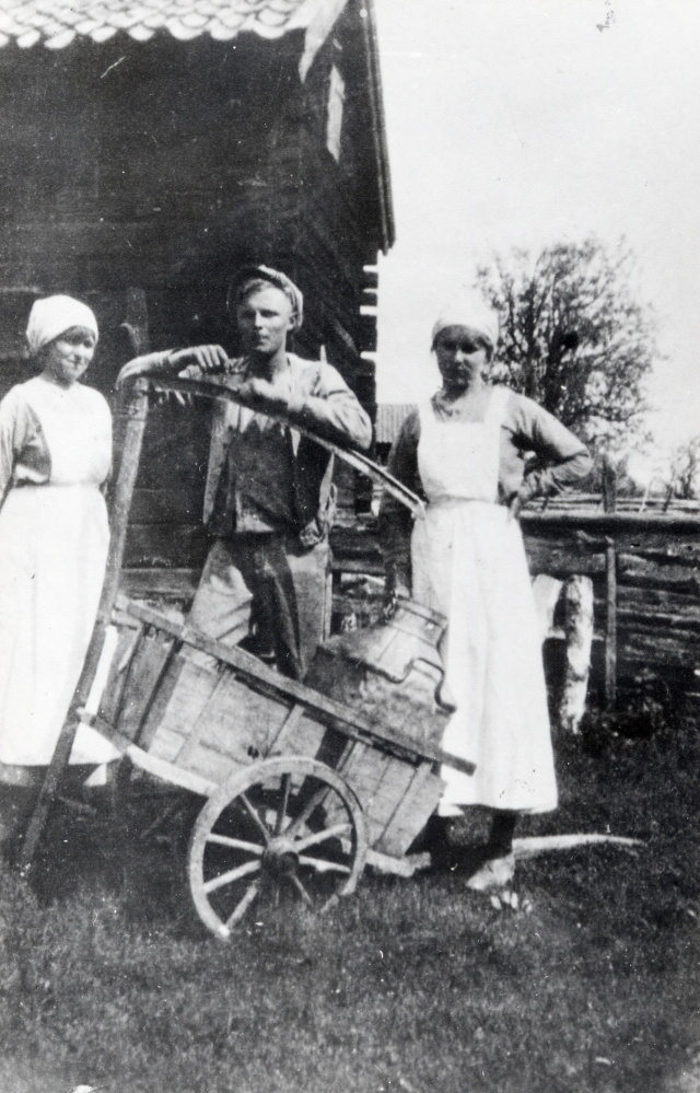 Mjölktransport med handdragen kärra. I kärran står en stor mjölkflaska av bleckplåt. Runt kärran står fr v Terèse Gustafson född 1892-09-12--, Gustav Gustafson 1896-09-27--1976-09-16,som står med en lie Gustav gifte sig med Signe Österberg, handlaren Konrad Österbergs dotter, och Lisa Gustafson 1898--