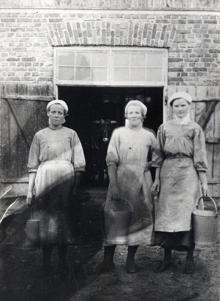 Mjölkerskor  utanför  ladugården  vid  Backa gård  T v  Terese Ländin  och t h  Nora Lundkvist  gift Zackrisson. I mitten ev en  mjölkpiga