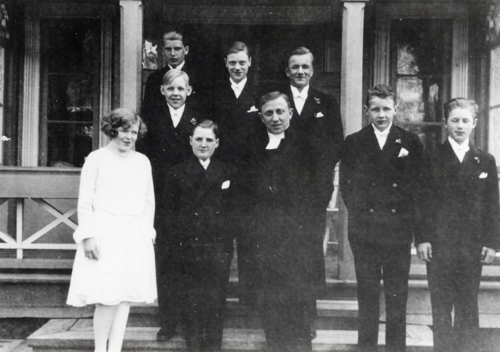 Kyrkoherde Olle Mattsson tillsammans med konfirmanderna utanför prästgården i Össeby-Garn.  I bakre raden längst t v står Stig Henningsson från Klippan i Vallentuna