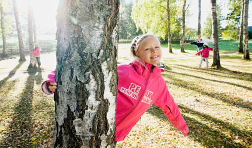 Elev som leker bland träd på skolgården på Hagaskolan