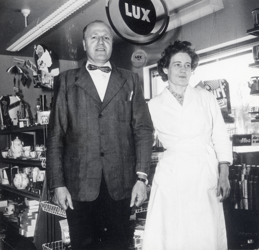 Hulda Maria Eriksson  och Gösta Eriksson  övertog  Sursta handel  1944. Nytt affärshus bygdes 1955 och var i drift till 1963. I affären fanns 1955-1975 en biblioteksfilial, vilken också sköttes av makarna Eriksson. Här står  Gösta Eriksson  och hustrun  Hulda Maria Eriksson  i den nya affären.  Se Lanthandlare i vallentunasocknarna vid Roslagsbanan