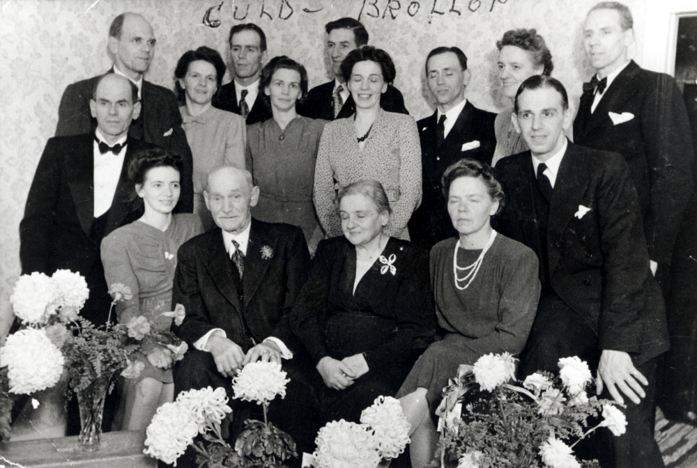 Elin och Emanuel Johansson gifte sig 1896 och bosatte sig på Helgö gård i Frösunda.  Paret fick 16 barn, 2 dog i späd ålder och en son i 14-årsåldern. Här sitter paret i salen på Helgö gård omgivna av 13 barn.  Nedre raden fr v Margit f 1914, Emanuel f 1868, Elin f 1876 och Helga f 1900. Bakre raden fr v Sven f 1897, Fredrik f 1898, Alice f 1908, Seth f 1910, Svea f 1906, Helge f 1903, Signe f 1911, Bengt f 1913, Karin f 1905, Karl Erik f 1917 och Gösta f 1902.  Föräldrarna hette Johansson men barnen antog släktnamnet Helgöstam på 1920-talet