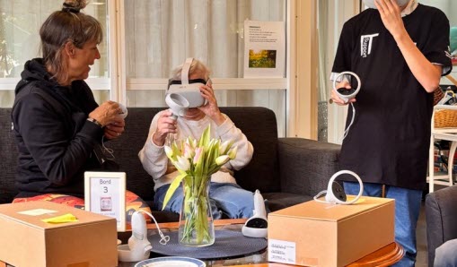 Elev visar senior och samordnare för Träffpunkten hur ett VR headset fungerar.