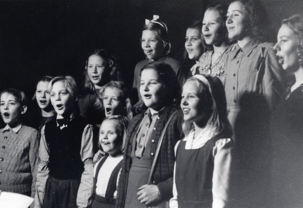 Vallentuna barnkör vid en inspelning på Radiotjänst i Stockholm ht 1947.  Fotograferat av Röster i Radio i studio 10 på Kungsgatan under en repetition före radioutsändningen. Bland körens medlemmar syns Monica Lööv, Inger Bornholm, Gun Lindersson, Siv Nyberg, Viola Wester, Ulf Bengtsson, Ove Segeblad, Marianne Larsson och Ingrid Johansson.