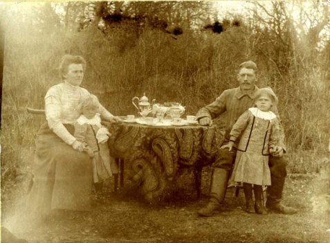 En familj som sitter vid ett bord ute i trädgården