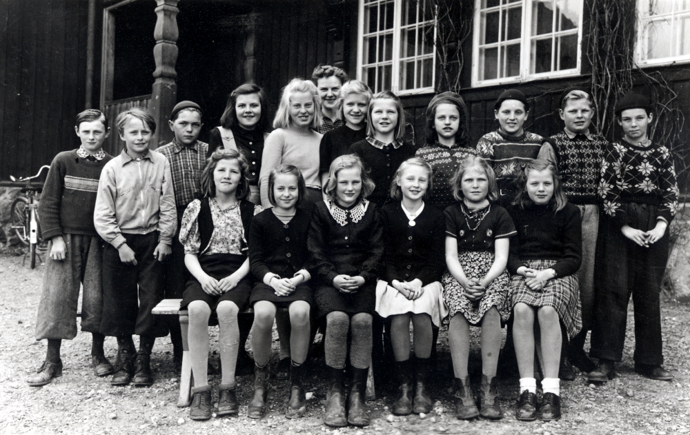 Hjälmsta skola.  Lärarinnan Kerstin Lundqvist tillsammans med skolbarnen utanför Röda skolan. Bakre raden fr v Ingemar Ernström, Lasse Johansson  "Sop-Johan", Sven Gustavsson, Hilda Sjöman, Sylvia Hansson gift Pettersson, Elvine Nee (Hilda och Elvine kom från Estland), Kerstin Karlsson, Barbro Jansson, Åke Karlsson, Toivo Tornaeus och Arne Gustavsson.  Sittande fr v Gunni Andersson,  Ingegerd Eriksson,  Lisbet Olsson, Lillian Ekstrand, Margit Hedlund och Kerstin Blomdahl. Bo Bengtsson, Ove Hahn och Margareta Vängby lämnade klassen efter  fyran och började i läroverk