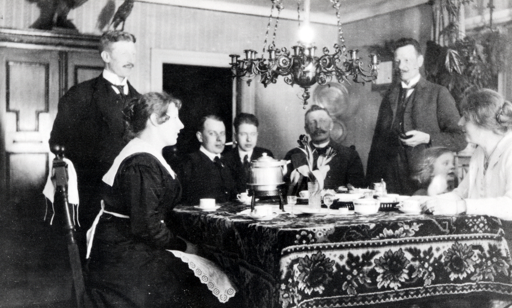 Samlade runt kaffebordet på Lilla Benhamra gård sitter fr v Helga Ahlén, Helge Ahlén, okänd, okänd, August Ahlén, Alfred 'Pelle' Lund och hans hustru Tyra Lund, född Ahlén med dottern Elisabeth Lund