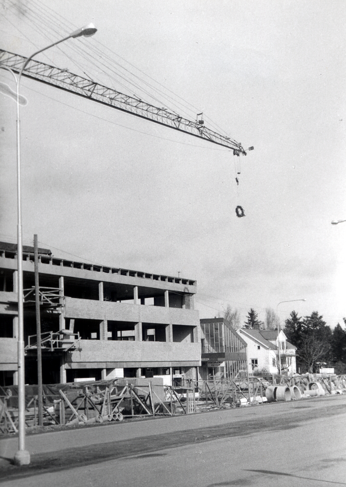 Taklagsfest  vid  Tunahuset   Först hissades en docka upp i masten. Den byttes ut mot en krans, som visade att byggnadsarbetarna skulle få sin taklagsfest.  T h skymtar  Konsum  och  Länssparbanken
