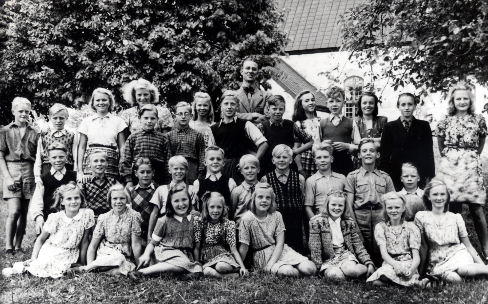 Gösta Sahlin med skolbarn i klasserna 5, 6 och 7 utanför Össeby-Garns kyrka.  I övre raden står fr v Karl-Erik Johansson, okänd, Vivian Kraemer, Maj-Britt Spets, Fritz Johansson, Tora Lundberg, Inez Jansson, Ingemar Wallbom, Maj-Lis Eklund, Arne Stjärnholm, Sonja Tullberg, Alf Eklund  och Inga Johansson.  Knästående fr v Per Lundin, Erik Forsberg, Erik Mattson, Rune Jansson, Ture Rödin, Holger Dahlbeck, Hasse Gustavsson, Karl-Gustav Spets, Lennart Lind och Rolf Degling.  Sittande fr v Gunilla Andersson, Ella Gustavsson, Ingrid Lindman, Kerstin Stjärnholm, Britt Pettersson, Ella-Görel Wetterwik, Ulla Franzén och Kerstin Balk