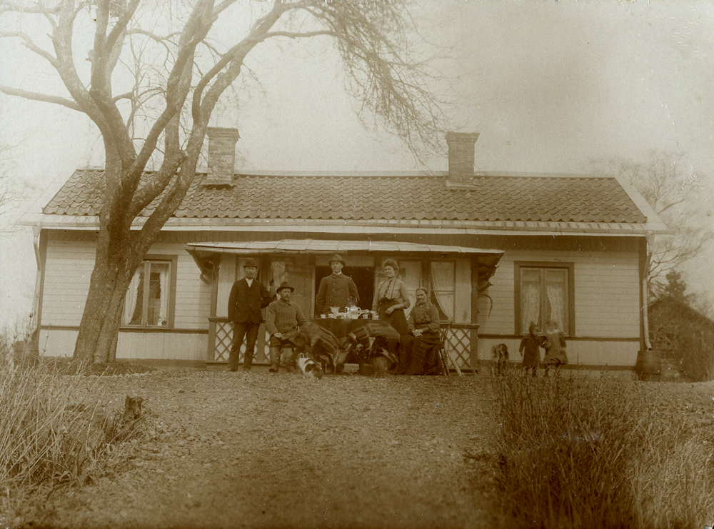 Utanför Grevelsta gård står August Ek, Isidor Ek, Calle (Ljung) Ek och Anna Ek, gift med August.  Den äldre damen kan vara mor till Calle,  August och Isidor.  Barnen t v är förmodligen Helga och Isidor Eks barn Irma född 1906 och Ester född 1908.  Calle tog soldatnamnet Ljung, men tog sedan åter namnet Ek.  August köpte och ägde en period  Viggbyholms gård i Täby