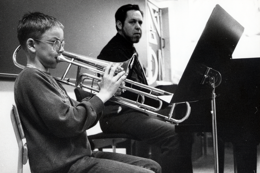 Rektorn vid Vallentuna musikskola, Kurt-Wallis Petersson, sitter vid pianot och lyssnar på elelven Mikael Hillbo som spelar ventiltrombon.  Lektion i musikskolans lokaler i Hammarbacksskolan