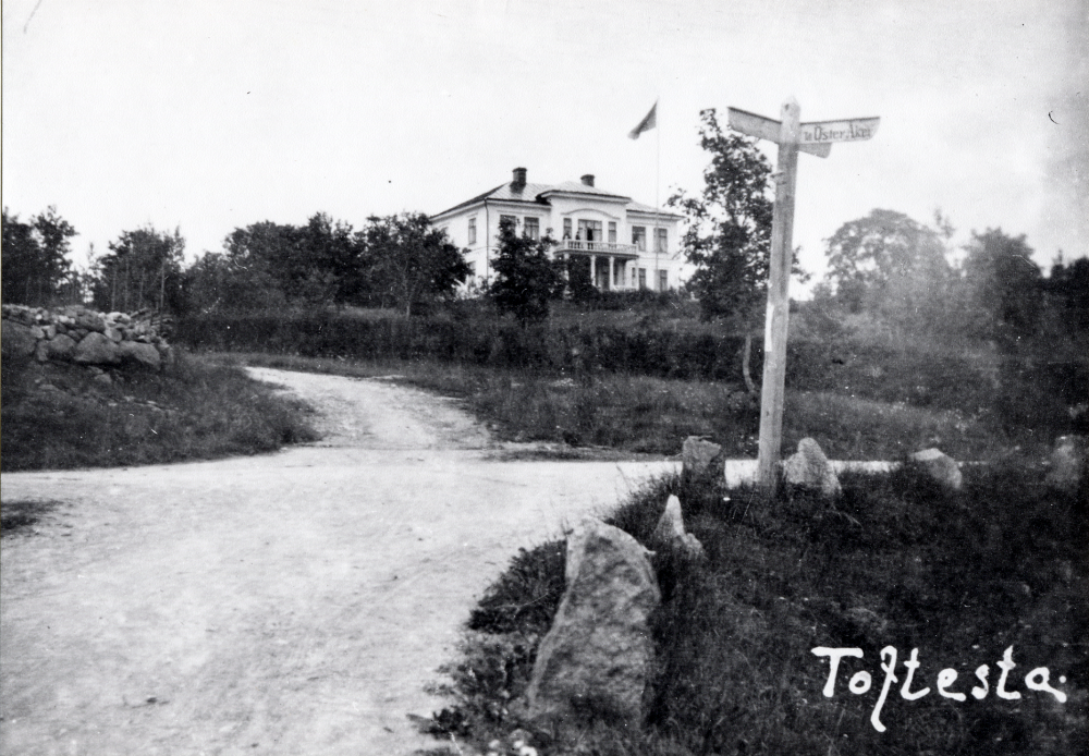 Toftesta gård byggdes 1907. Nedanför gården står en vägvisare med pil mot Öster-Åker
