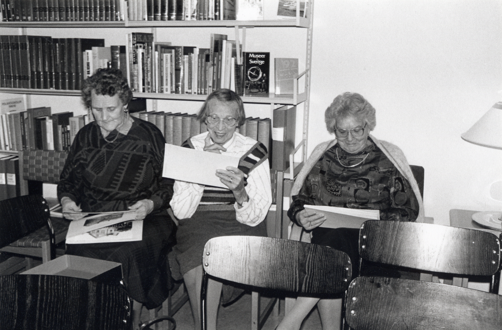 Gun Hillbo berättar om Vallentuna bildarkiv i Karby bibliotek. Tre damer tittar i bildlådorna,  fr v Hilda Sjöman, Rosa Johansson och Ally Backlund