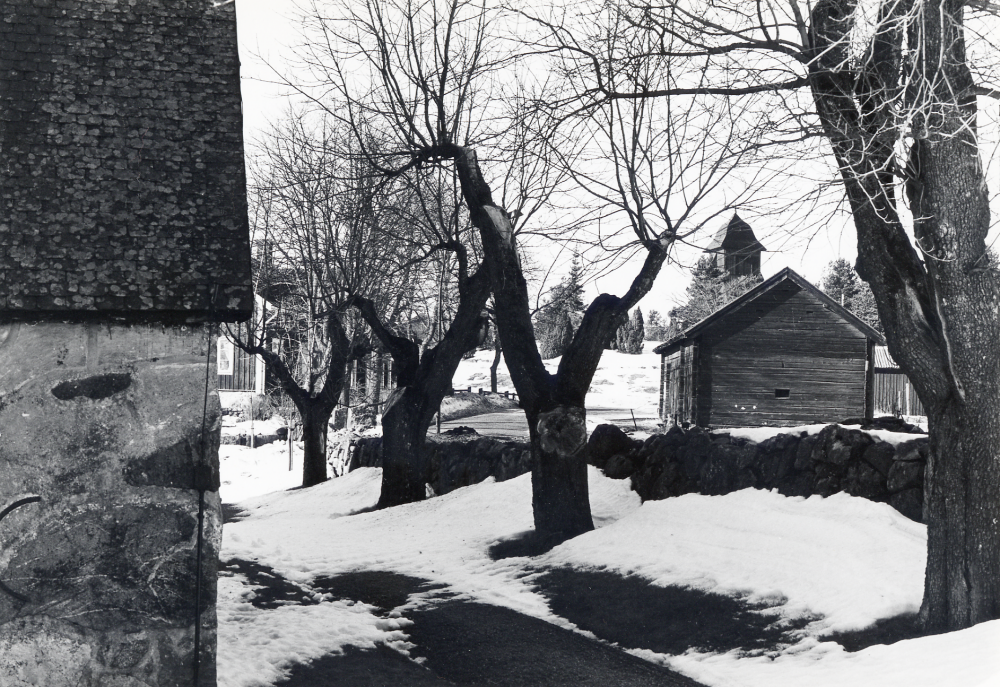 Kårsta kyrkogård. T v syns Kårsta kyrka och t h ovanför ladan syns klockstapeln. Mellan träden skymtar Kårsta skola
