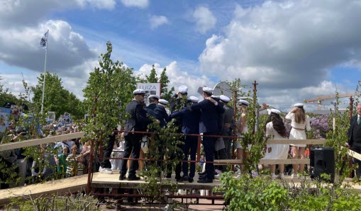 Gymnasieelever som står på ett träpodie och firar studenten.