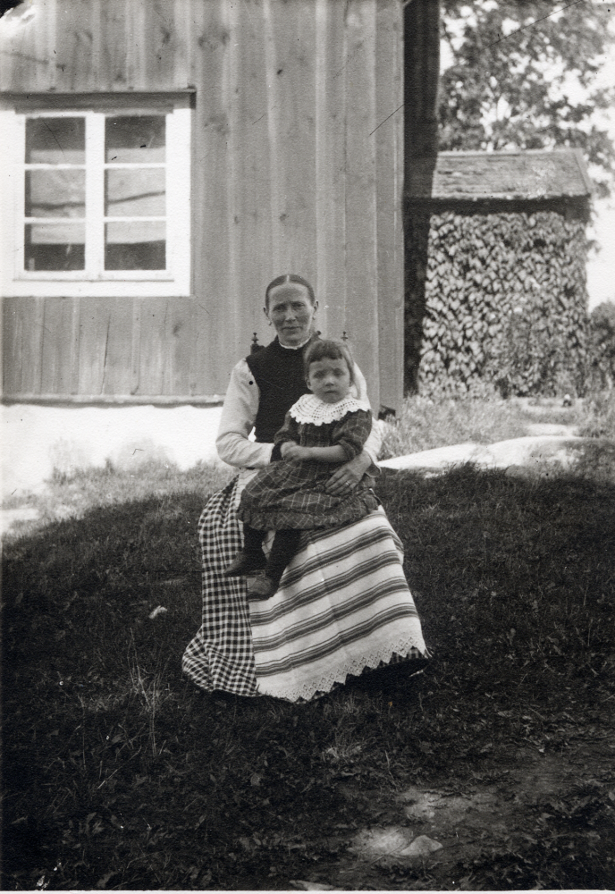 Josefina Lindgren  vid  Skrävsta klädd i ett randigt  förkläde och med ett litet barn i knäet.  Ev var Josefina född  Golmodin