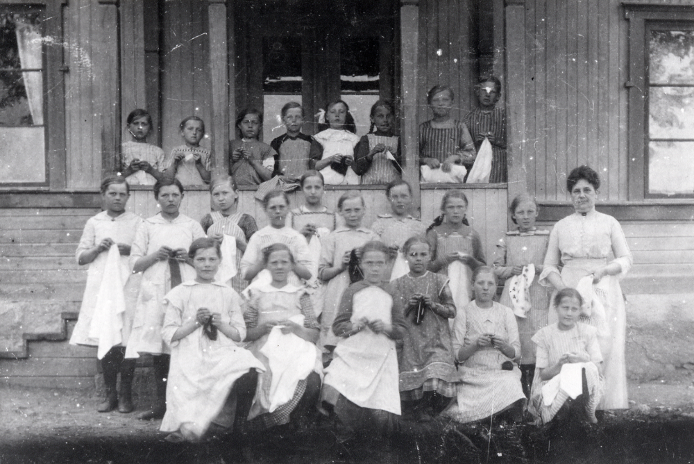 Lärarinnan Anna Österberg, senare gift Mattsson, med flickorna på trappan utanför Torsholma skola i Frösunda. Övre raden fr v nr 2 Inez Hermansson, nr 3 Astrid Jansson, nr 5 Lisa Jansson, nr 6 Ellen Juhlin. Mellanraden fr v nr 1 Karin Konstance Eriksson, nr 3 Elsa Johansson, nr 6 Elsa Mattsson, nr 7 Maria Gustavsson, nr 8 Svea Lundkvist, nr 9 Märta Johansson. Sittande fr v Ingeborg Lindblom, Elin Andersson, okänd, Greta Frid, Svea Johansson och Signe Hermansson