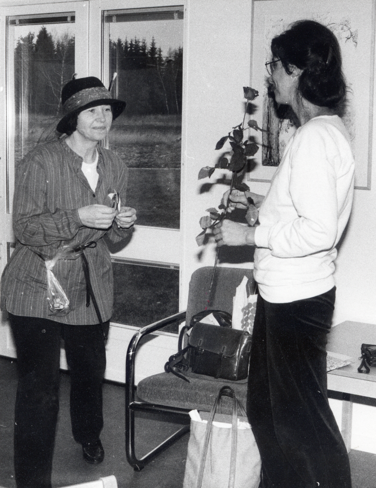 Eva Rahmqvist har fyllt 40 år.  Här firas hon av personalen på Vallentuna bibliotek.  Festen äger rum i Lindholmens bibliotek.  Margareta Dethorey har just lämnat över en ros till födelsdagsbarnet