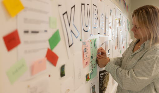 Lina sätter upp skapelser på KUBenStories vägg på Karby Corner.