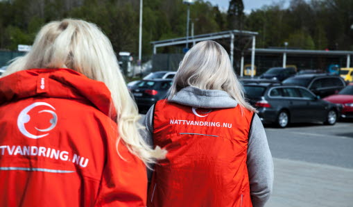 Fyra personer i röda jackor som går på en väg