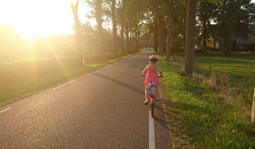 Flicka som cyklar på en solig väg
