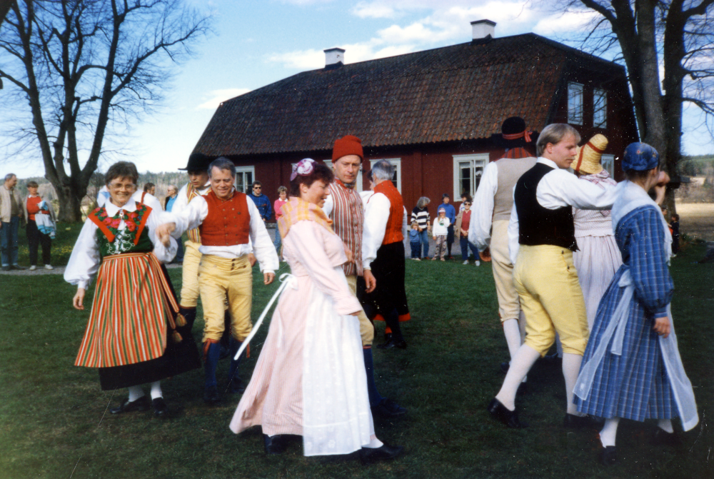 Medlemmar i Vallentuna folkdansförening dansar i ett program på Stora Benhamra. Bakre paret är Elvy och Börje Sundberg, i mitten Lotta och Lennart Zackrisson, t v Marita Lagergren och Mikael Lindberg samt längst fram i dansen Yngve Åstrand och Marianne Forslund. Bakom Börje skymtar Ingvar Nyman och i mitten syns ryggen på Ingmar Unnerstad