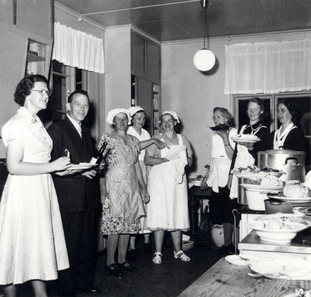 Ingegärd Eliassons och Stig Öhmans bröllopsfest i Ekskogens bygdegård.  Bland grytor och fat i köket står fr v Ingegärd Pettersson, Anselm Pettersson, Helga Pettersson i Tallen, Frida Berg,  Anna-Lisa Larsson, Tyra Karlsson, Anna Lundkvist och Inga-Britt Eriksson.  I för- grunden ser man en potatiskarott och fat med bl a blomkål