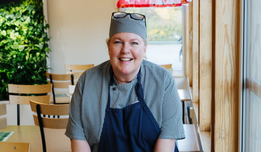 Kökspersonal ler mot kameran i matsalen.