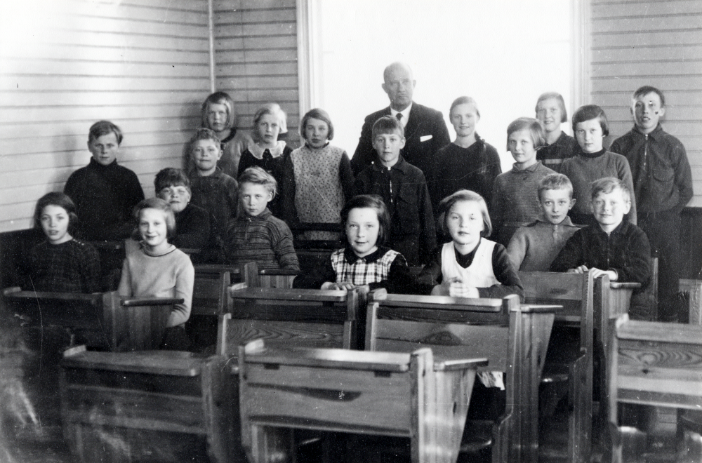 Vada skola.  Läraren Brynolf Fromm tillsammans med skolbarnen i skolsalen. Fr v Marta Karlsson, Seved Eriksson, Ingrid Wester, Harry Nordkvist, okänd, Anna ?, Lisa Nordkvist, Roine Bjurström, Anna-Lisa Ahlén, okänd, Ingegerd Fredriksson, okänd, Wivi Wallin, (bredvid Fromm), okänd, Maj-Britt Johansson, Ingegerd Singfelt, Edgar Axzell, Maj-Lis Johansson, ? Johansson, Ruben Bewner.