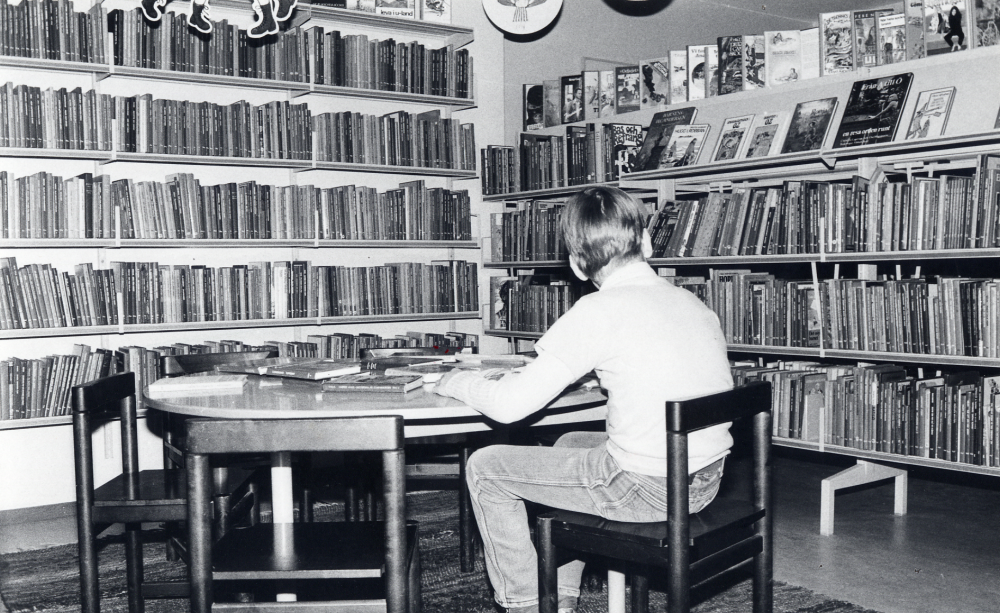 Interiör från Karby bibliotek, Tallstigen.  Mikael Hillbo sitter i barnavdelningen, en "hörna" inramad av bokhyllor