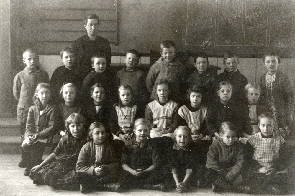 Lärarinnan Anna Gauffin tillsammans med skolbarnen i Röda skolan, Hjälmsta 1925, det år då skolan invigdes.  I bakre raden nr 2 fr h Hjalmar Lind, nr 3 Ragnar Pettersson?.  Mellanraden nr 4 fr v Ingrid Jansson