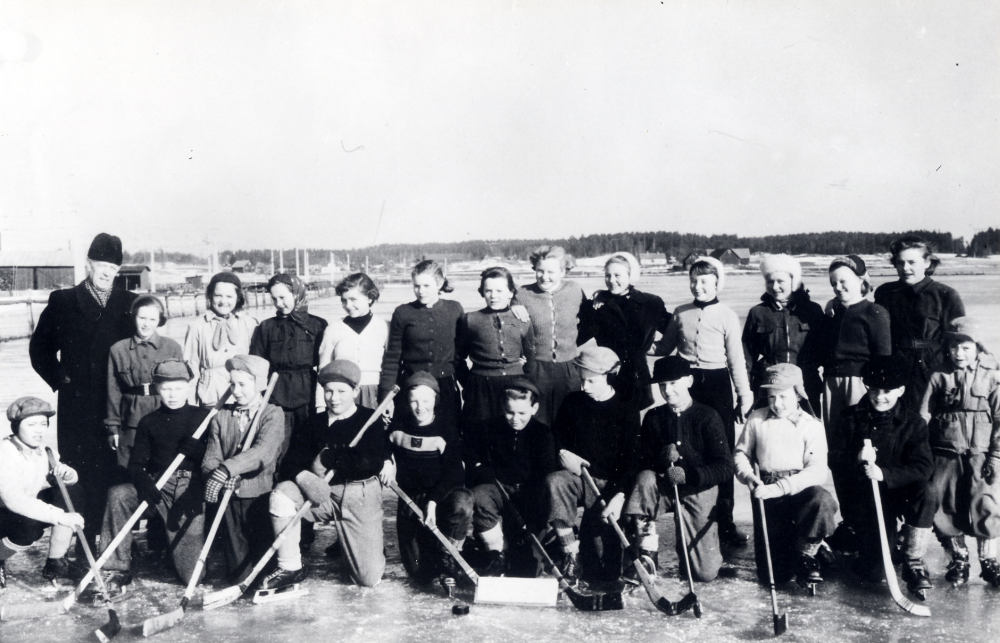Läraren  Gustaf Sundman  tillsammans med skolbarnen på Prästgårdsängen  där översvämmat vatten frusit till is, för att åka  skridskor  Övre raden fr v  Ulla Eriksson   Mona  Andersson-Sahlberg,  Desiré Andersson, Inga Helgöstam, Siv  Pettersson,   Irene Jansson   Birgitta Berglund   Siv   Nilsson   Kristina Lundkvist   Gun-Marie Karlsson   Gerd Pettesson  och  Maud Söderström  Andra raden fr v:  Arne Stolpe   Rolf-Arne Jansson   Arne Jansson   Lasse Wredh   Bo Eriksson   Kjell Helgöstam   Bo Lundin   Olle Johansson   Tore Eriksson   Lennart Sahlberg  och  Sune Eriksson bbror till Tore