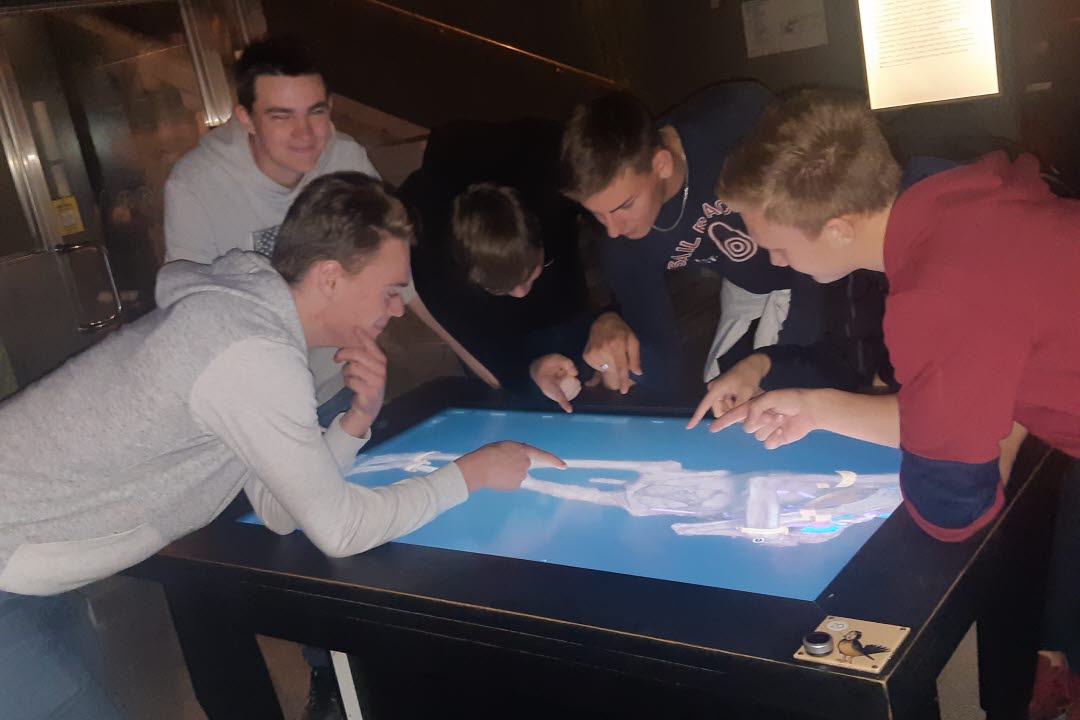 Ett gäng ungdomar som står böjda över och tittar ner på en datorskärm