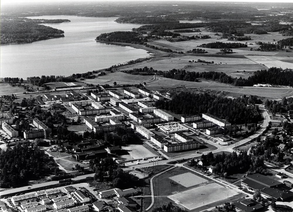 Flygfoto över bostadsområdet Norrgården och Sörgården. I bakgrunden syns Vallentunasjön.  Vägen i bildens mitt är Teknikvägen. Norr om vägen syns t v bostadsområdet    Mörbygården och t h Hammarbacksskolan med fotbollsplan