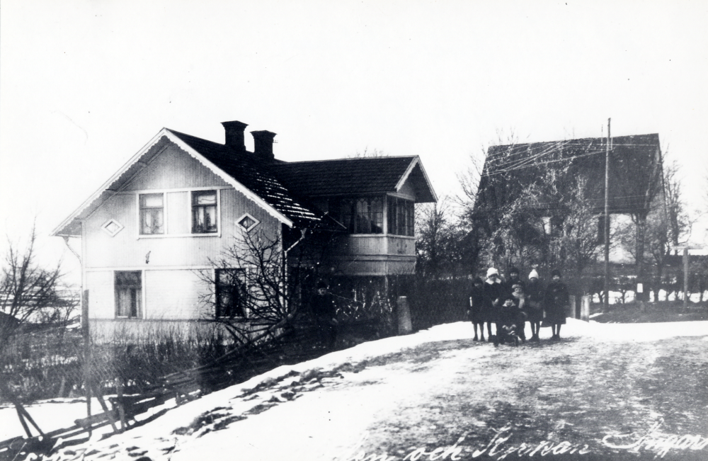 Karlborgs handelsbod med Angarns kyrka t h. Några flickor står på vägen utanför affären, längst t h Karin Lundin gift Edman, innehavarens dotter.