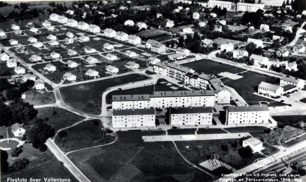Flygfoto över Vallentuna med Centralvägen i bildens mitt, Vallentuna kommunalhus t h och det nybyggda Prästgårdsgärdet tv med HSB-husen vid Allévägen.  I  bildens övre del syns kvarteren norr om Allévägen med den gamla villabebyggelsen vid Mörbyvägen, Sommarvägen och Källvägen.  I bakgrunden skymtar flerfamiljshus vid Fornminnesvägen