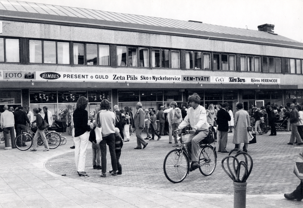 Det gamla Konsumhuset har byggts om för att rymma flera olika affärer.  I övervåningen finns Vallentuna bibliotek kvar.  Mycket folk har samlats på Tuna torg för att var med om invigningen av Torghuset