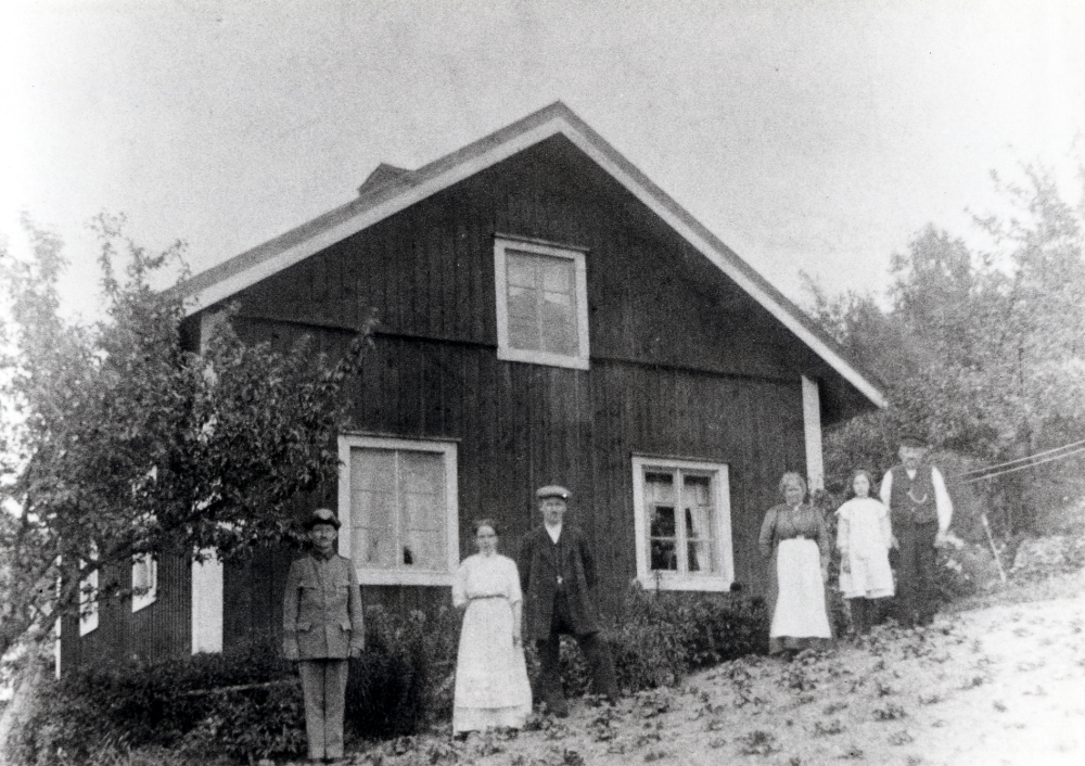 Stora Charlottenborg i Össeby-Garn.  Framför gaveln står fr v skomakare Per Gustav Nilsson i uniform, Lina Nilsson, Erik Gottfrid Nilsson (bror till Per Gustav) , Charlotta Nilsson (dog ca 1938), fosterdottern? Emmy Philgren och skomakare Erik Gustav Nilsson (död 1930).  Erik Gustav och Charlotta var föräldrar till Per Gustav.