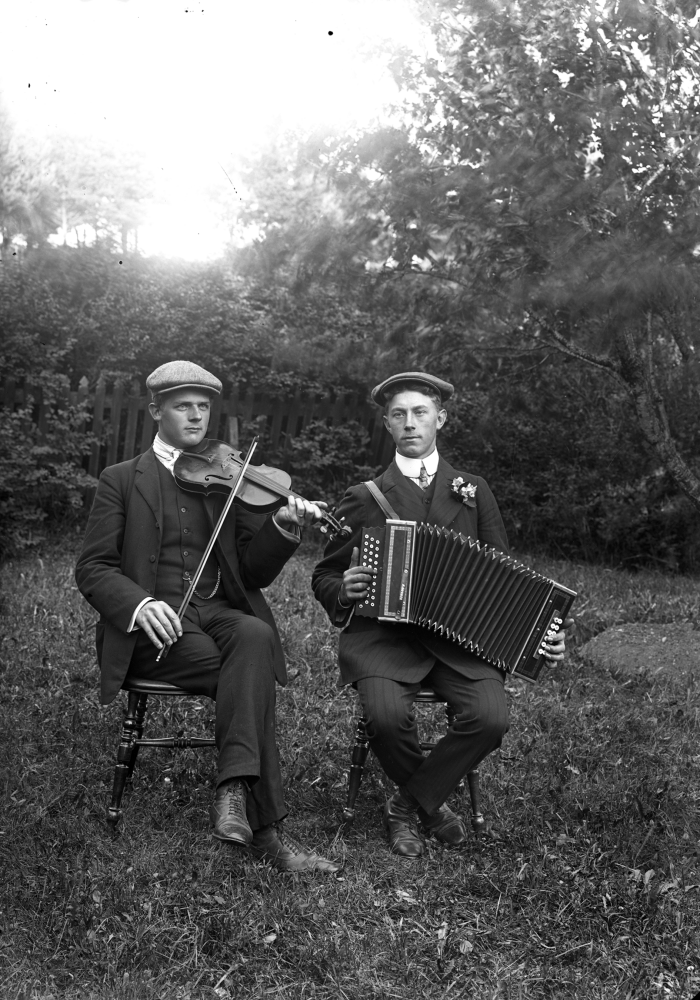 Två musikanter spelar fiol och dragspel. Platsen är okänd. Uppgift om fotoår saknas, men troligen 1920-talet.
