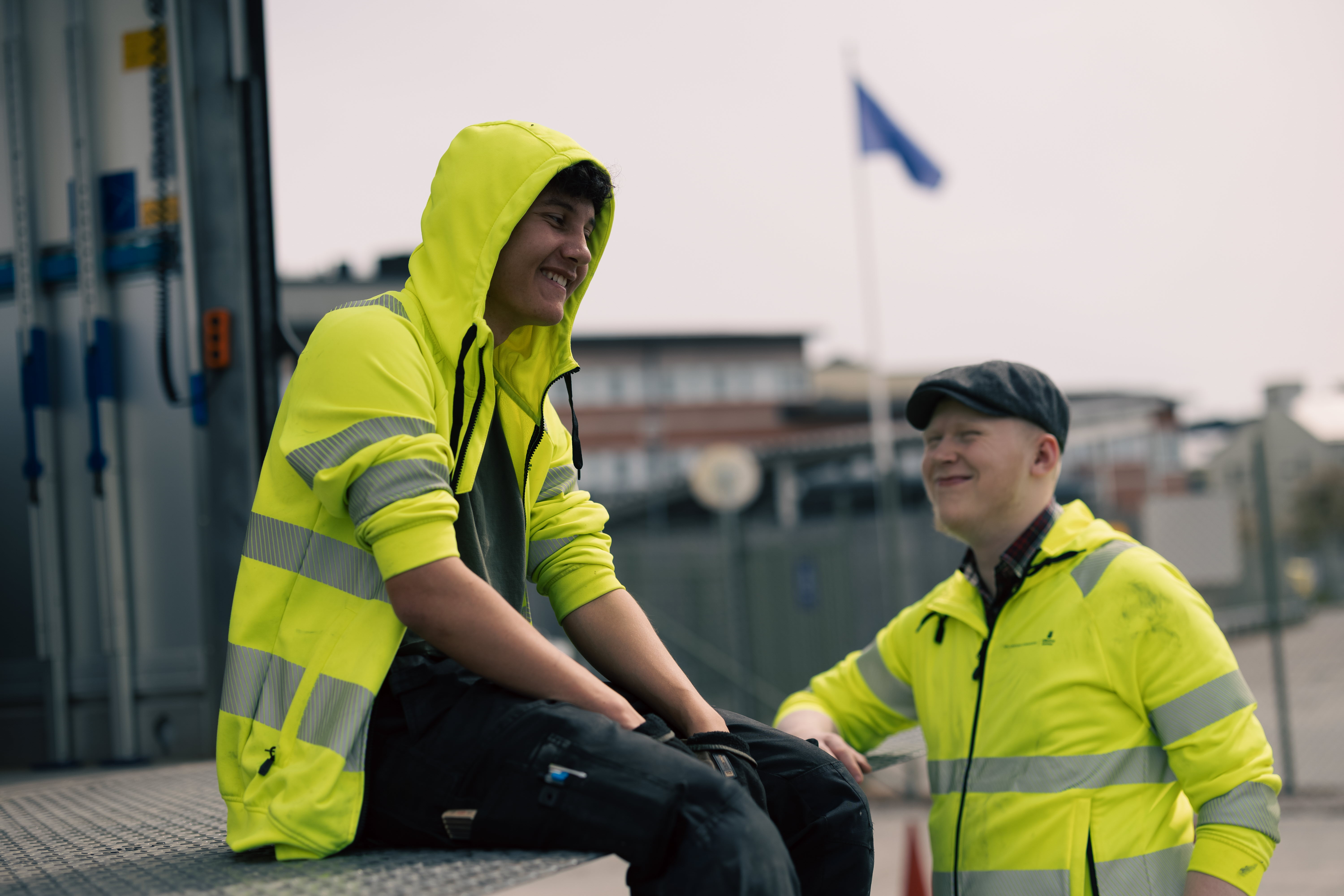 Två elever umgås intill programmets lastbil. En sittandes på flaket av lastbilen och den andra ståendes intill.