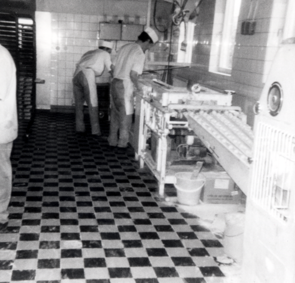 WT-bageriet stod färdigt 1955 och byggdes ut mot norr 1962.  Det byggdes och ägdes av Inga-Britt och Inge Englund, som också bodde i lägenheten ovanpå bageriet.   I bageriet bakade man från början kaffebröd, bakelser, tårtor och småkakor, som mest hade bageriet 19 anställda. När bageriet byggdes ut mot norr installerades en stor oljeeldad automatisk tunnelugn.  Den var den första i sitt slag i Sverige och byggdes som prototyp. Nu bakade man framförallt skorpor, 
8 000 runda bullar i timmen, vilka delades och blev till 16 000 skorpor.  Skorporna var välkända och såldes ända ner till Skåne.  Stockholms landsting köpte 75 ton av skorporna varje år.  T v står Kurt Edvardsson, som tidigare arbetat i Martin Linders bageri i Täby kyrkby, och Bengt Forsberg "Bagar Bengt". Bageriverksamheten lades ner vid årsskiftet 1975-76.