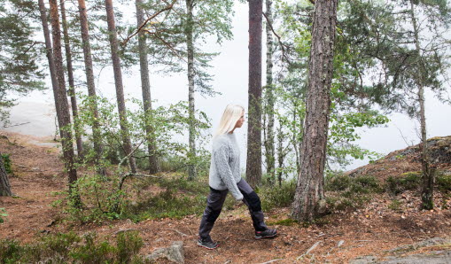 En kvinna vandrar på en stig längs vattnet.