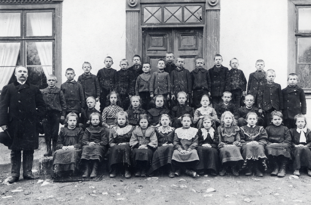 Läraren och organisten Per Ferdinad Torell tillsammans med skolbarnen utanför Klockargården Pojken i andra raden nr 2 från höger är Carl Johansson? Oppgården