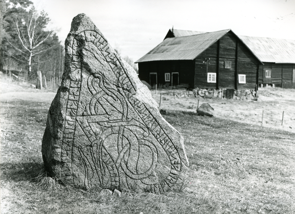 Runsten U233 i Kusta, strax utanför gårdsplanen, norr om mangårdsbyggnaden.