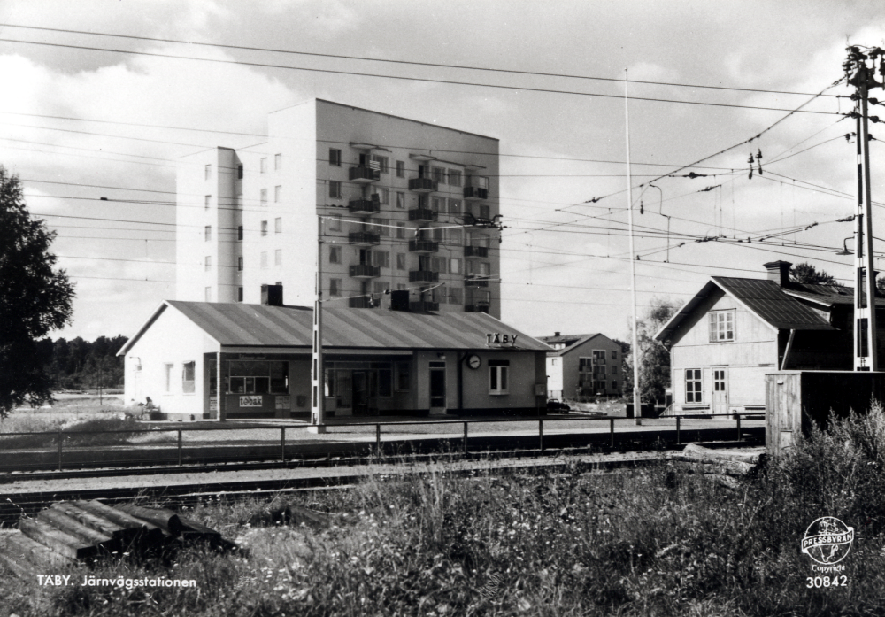 Täby järnvägsstation med det ensamma höghuset i bildens mitt.  Det gamla stationshuset finns ännu kvar