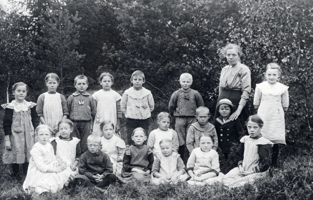 Lärarinnan Maria Nyberg tillsammans med skolbarnen i Salby skola. Maria Nyberg dog i slutet av 1920-talet. Övre raden fr v Ingrid Jansson, Helny Johansson, Eskil Gustavsson, Svea Karlsson, Sten Ahlgren, Olle Andersson och Elsa Berg. Nedre raden fr v Vera Elmqvist, Greta Åberg, Gunnar Öhman, Margit Elmqvist, Judit Lindkvist, Stina Lillje, Märta Andersson, Helmer Bergström, Elsa Andersson, Erik Cederlund och Maria Eklöw