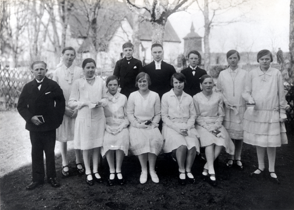 Prästen Röberg med konfirmander utanför Frösunda kyrka .Stående i övre raden fr v Karin Hermansson, Skräfsta, Gunnar Laurell, Wasa, Henry Hillers(s)on? och Svea Öhman.  Främre raden Harald Jansson, Anna-Lisa Fröman, Karin Nyberg, okänd flicka från Stolp-Ekeby, Helmy Ekström, Grebylund, Hedvig Johansson, Lindholmstorper, men var hos en moster i Skräfsta och Eivor Pettersson, utanför Grebylund