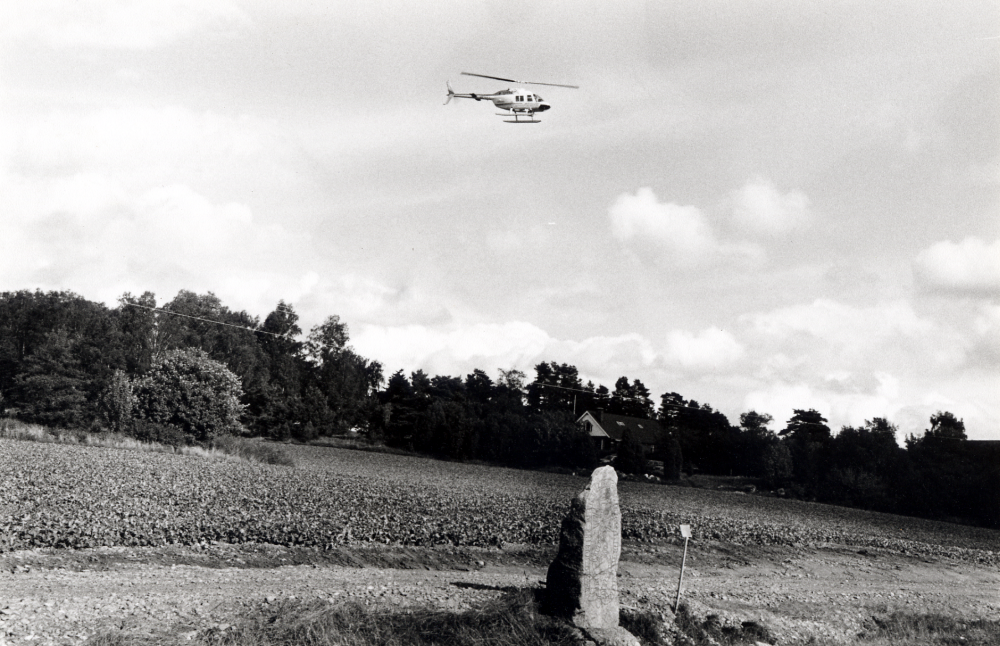 Lions flyg- och motordag på Vallentuna flygplats.  En helikopter gör uppstigningar och flyger över Väsbyvägen och runsten  U 236